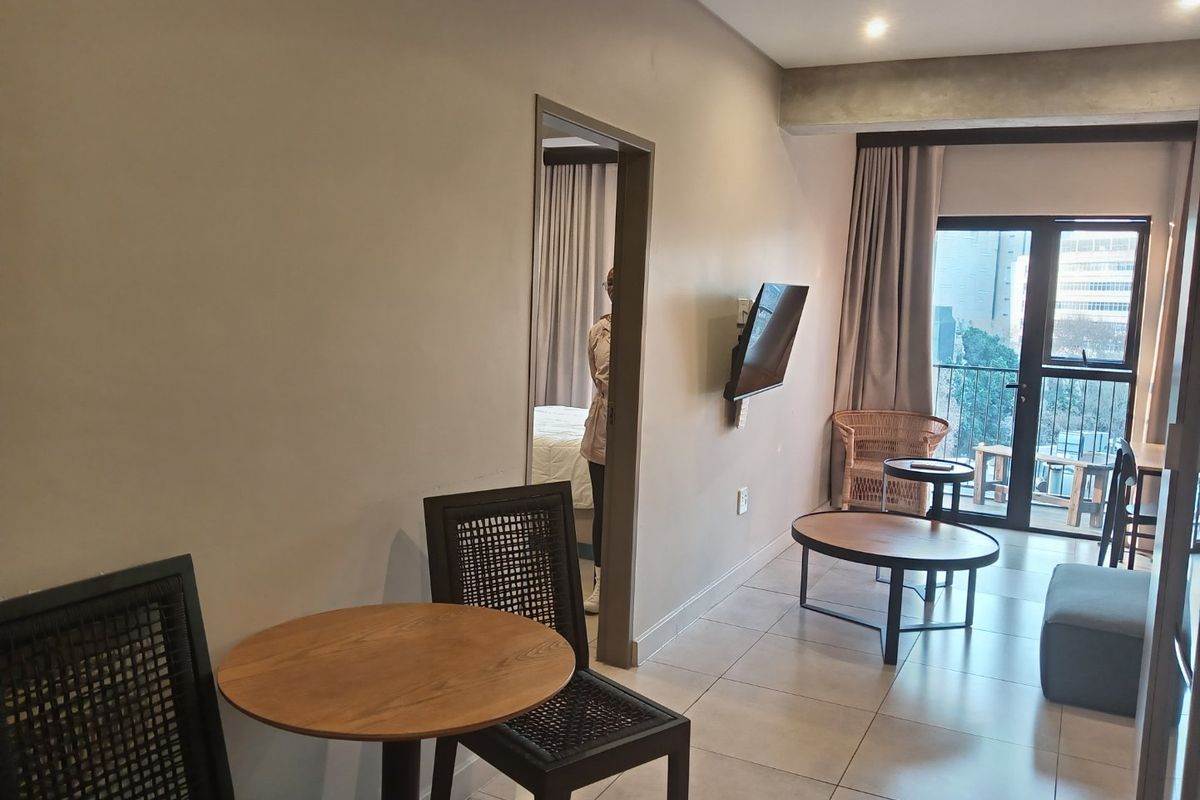 Open-plan living area featuring tiled flooring, recessed lighting, and direct access to a private balcony through a glass door.