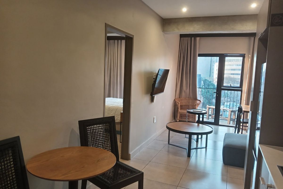 Open-plan living area featuring tiled flooring, recessed lighting, and direct access to a balcony through a sliding glass door.