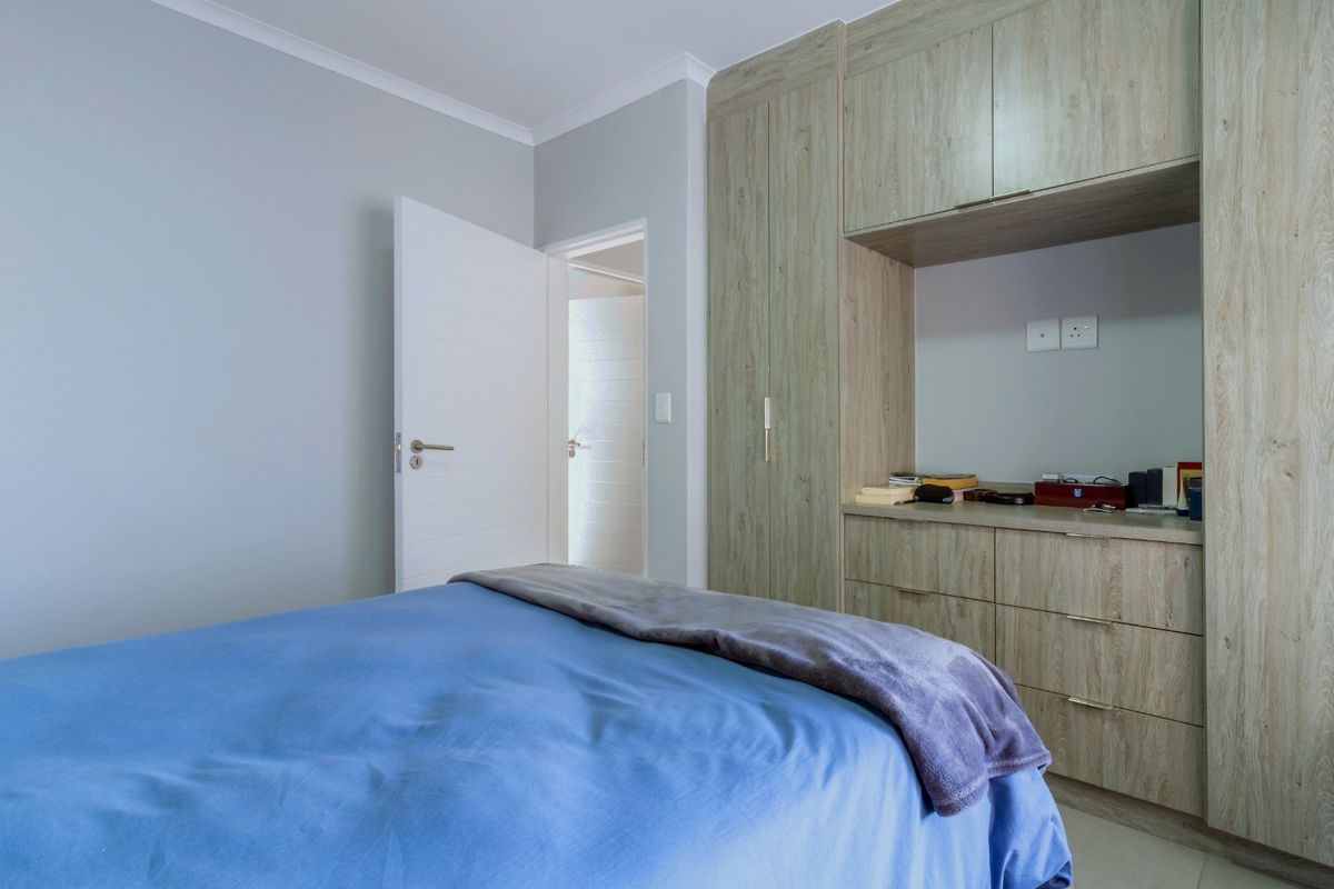 A well-maintained bedroom featuring modern built-in cupboards with an integrated vanity unit and neutral wall finishes.