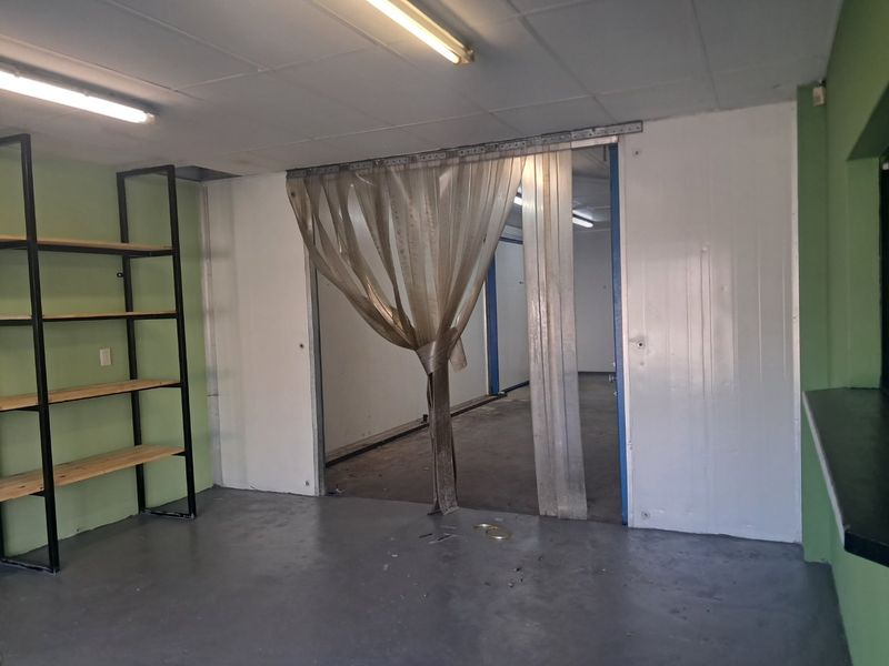 Utility space featuring industrial strip curtains, fluorescent lighting, and durable epoxy flooring, suitable for storage or commercial prep area.