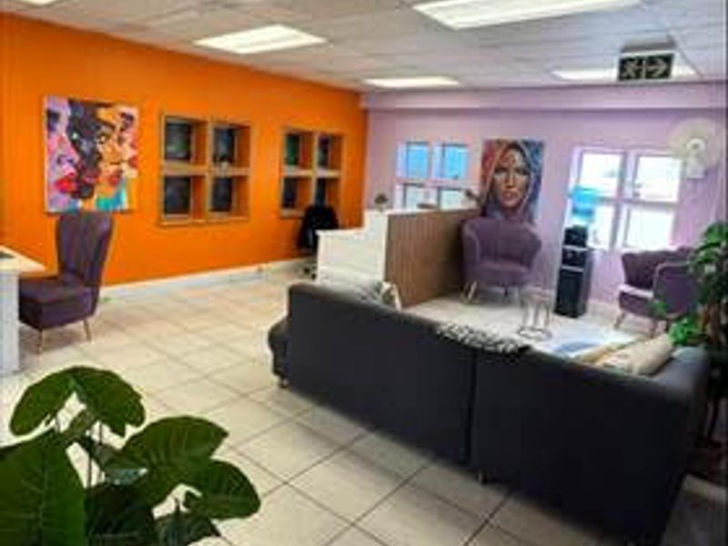 A commercial office space featuring a reception area, tiled flooring, and a suspended ceiling with recessed lighting.