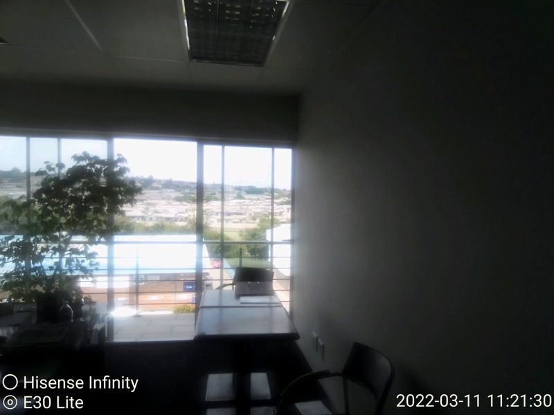A commercial office space featuring recessed ceiling lighting and large glass sliding doors that provide natural light and access to an outdoor balcony area.