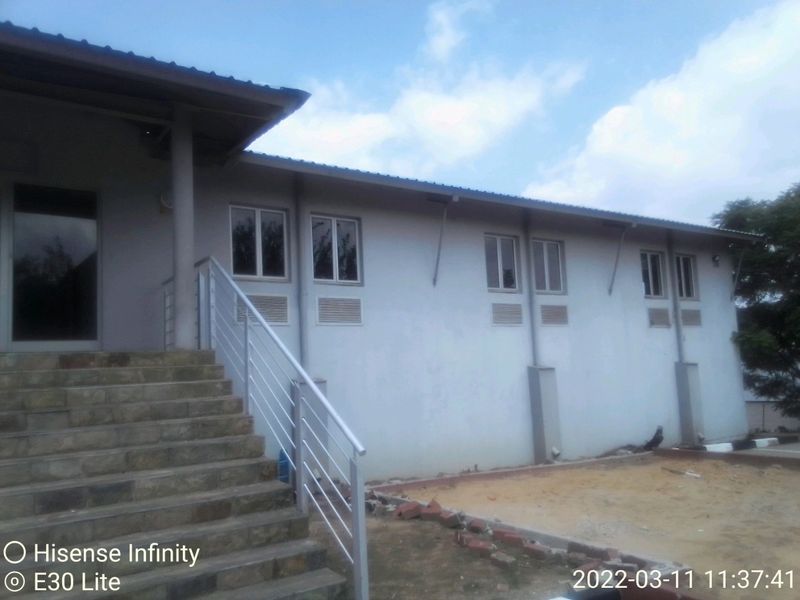 Exterior view of a commercial building featuring a stone staircase with metal railing, multiple windows, and wall-mounted air conditioning units.