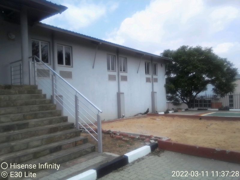 Rear exterior view of a commercial building featuring a concrete staircase with metal railings, paved areas, and a sand pit.