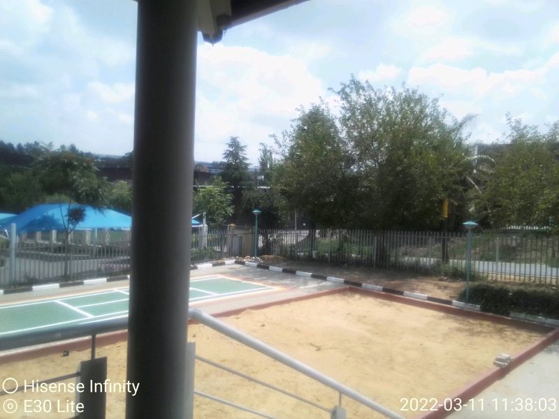An elevated view from a balcony overlooking a commercial outdoor recreational area featuring a sand pit and paved sports surface.