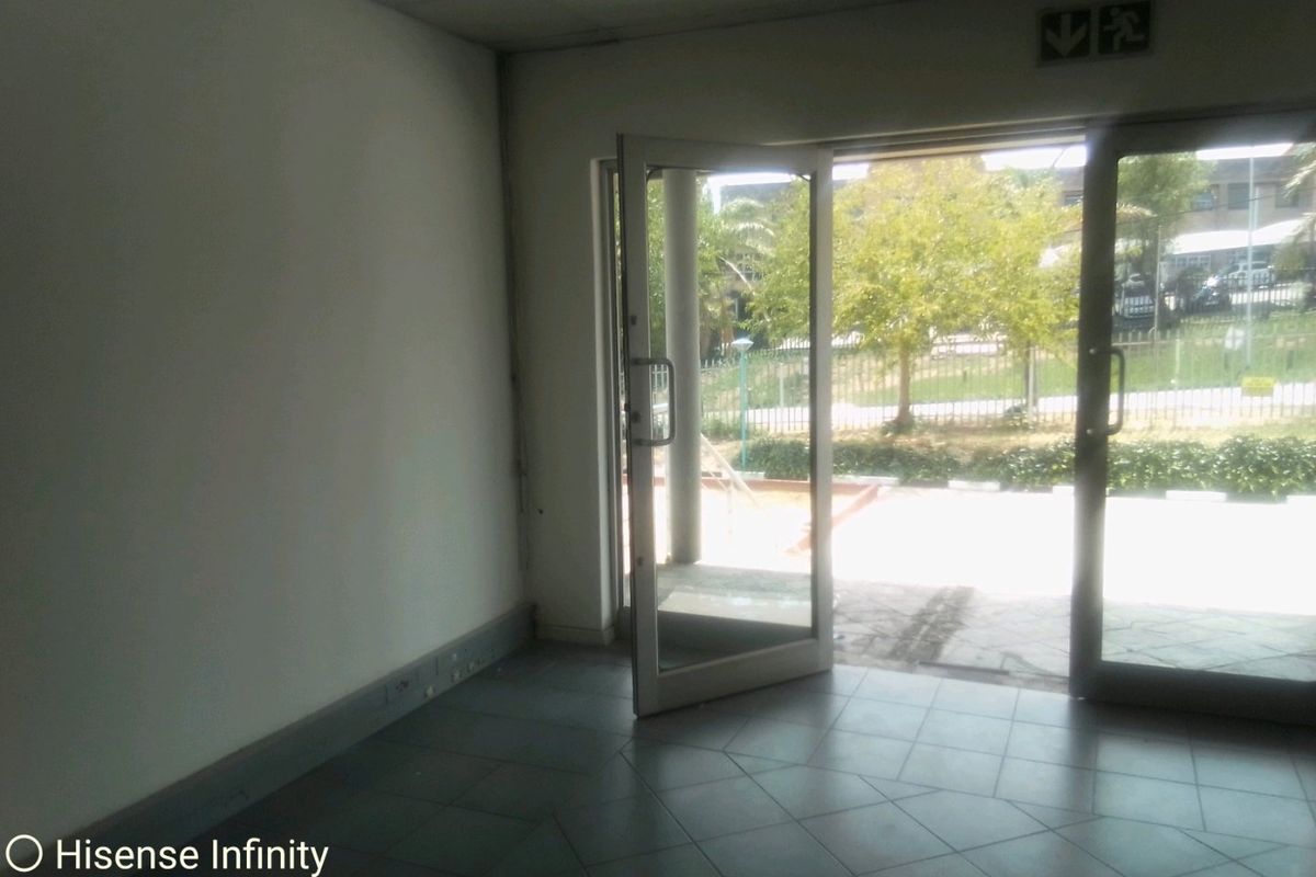 An empty commercial entry space featuring tiled flooring, a suspended ceiling, and a glass door leading to an outdoor area.
