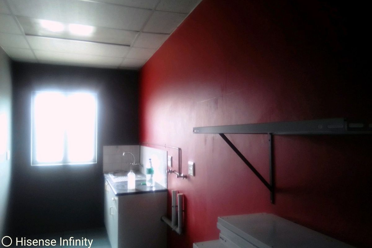 A small, empty kitchen area featuring a sink, built-in cabinetry, and wall-mounted shelving, requiring cosmetic updates to improve functionality and aesthetic appeal.