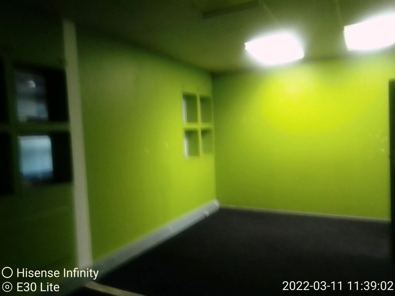 An empty office space featuring bright green walls, dark carpeting, and recessed ceiling lighting.