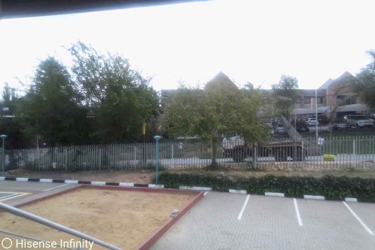 Exterior view of a commercial property featuring a paved parking area, a sand pit, and secure metal fencing.