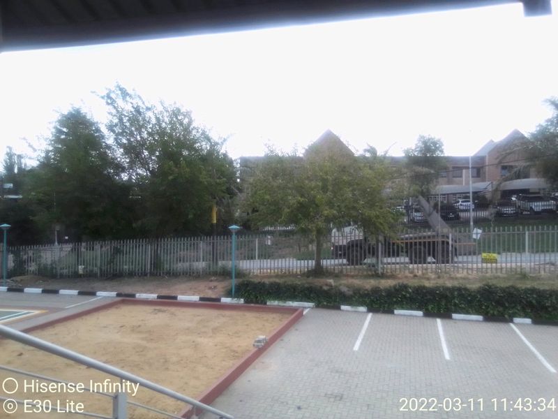 Exterior view of a commercial property featuring a paved parking area, a sand pit, and secure metal fencing.
