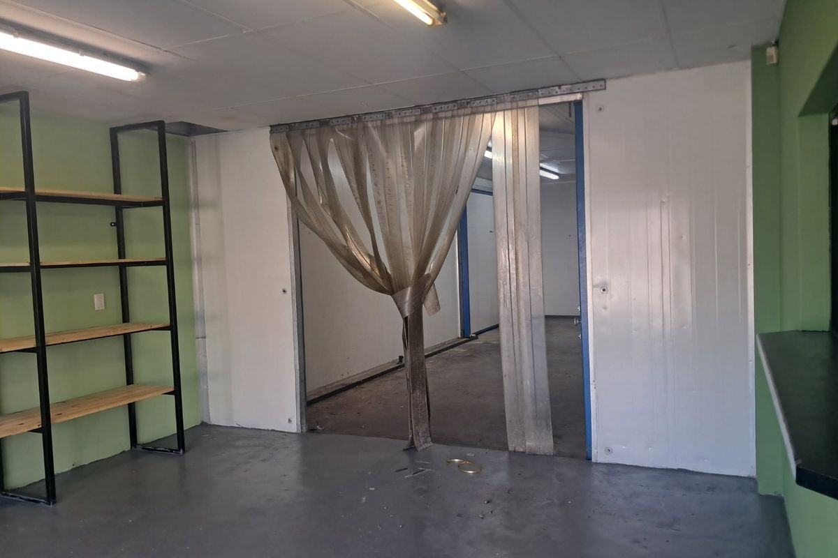 Industrial utility space featuring insulated wall panels, durable epoxy flooring, built-in metal shelving, and a PVC strip curtain partition.