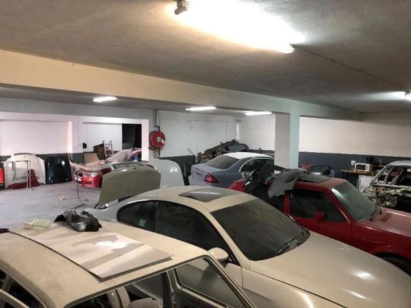 Spacious commercial garage area featuring concrete flooring, structural support columns, and overhead fluorescent lighting, suitable for automotive storage or workshop use.