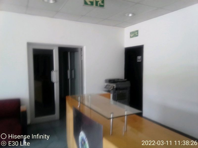 Commercial office entry area featuring a reception desk, suspended ceiling with recessed lighting, and glass panel doors.