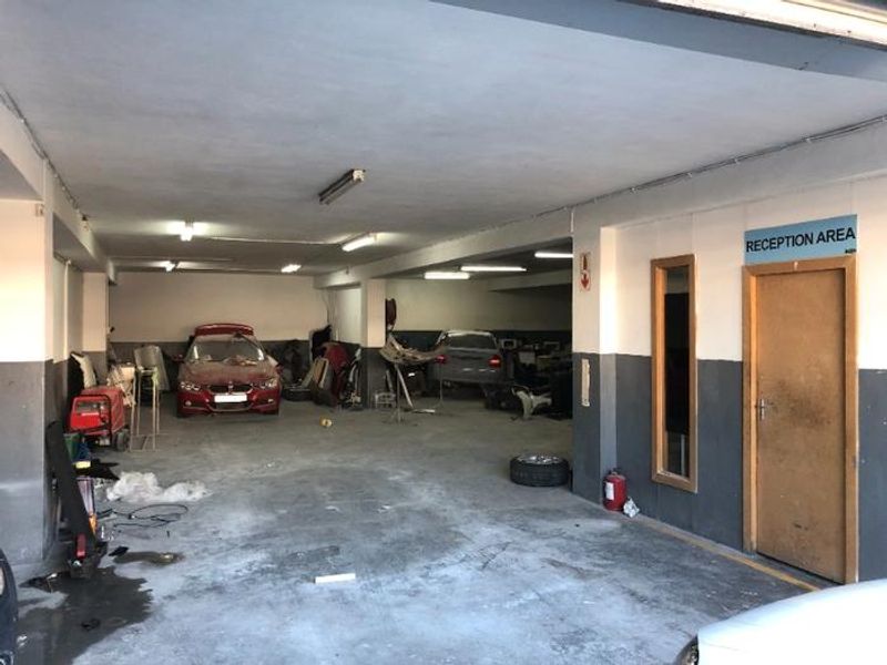 Spacious commercial garage or workshop area featuring concrete flooring, fluorescent lighting, and a dedicated reception access point.