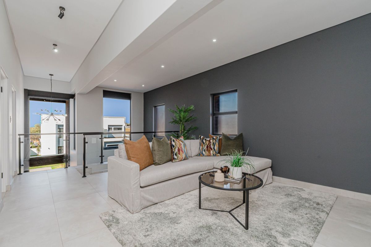 Modern living area featuring tiled floors, recessed lighting, and a glass balustrade overlooking the staircase void.