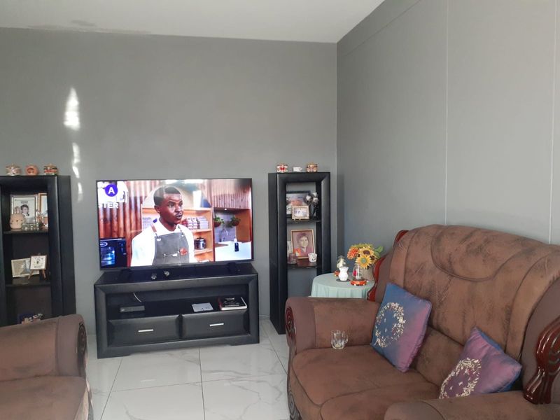 A living room featuring neutral grey walls and light-colored tiled flooring, providing a clean and functional space for relaxation.