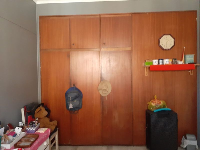 A bedroom featuring a full-wall built-in wooden wardrobe with overhead storage compartments.