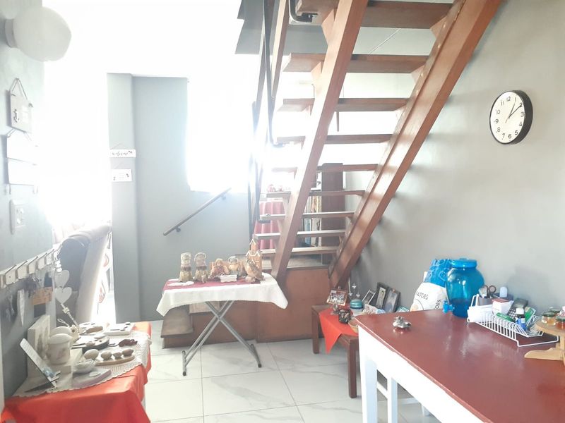 Living area featuring a wooden staircase and tiled flooring, providing access to the upper level of the apartment.
