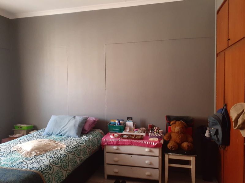 A bedroom featuring a built-in wooden wardrobe and neutral wall finishes, offering a functional space for rest.
