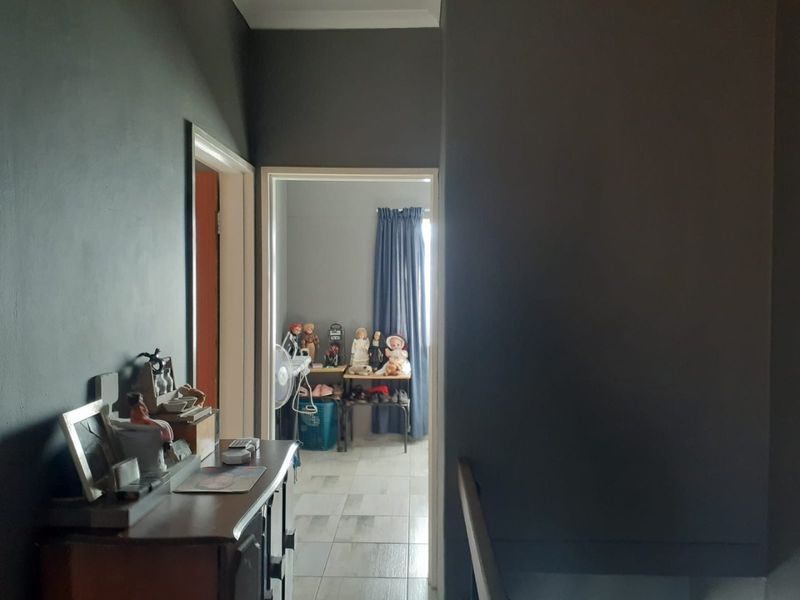 A view through a hallway into an adjacent room, featuring dark painted walls and tiled flooring.