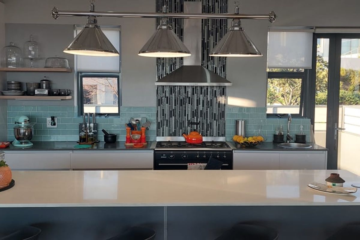 Modern kitchen featuring a large central island, quartz countertops, subway tile backsplash, gas stove with extractor, and direct access to an outdoor area.