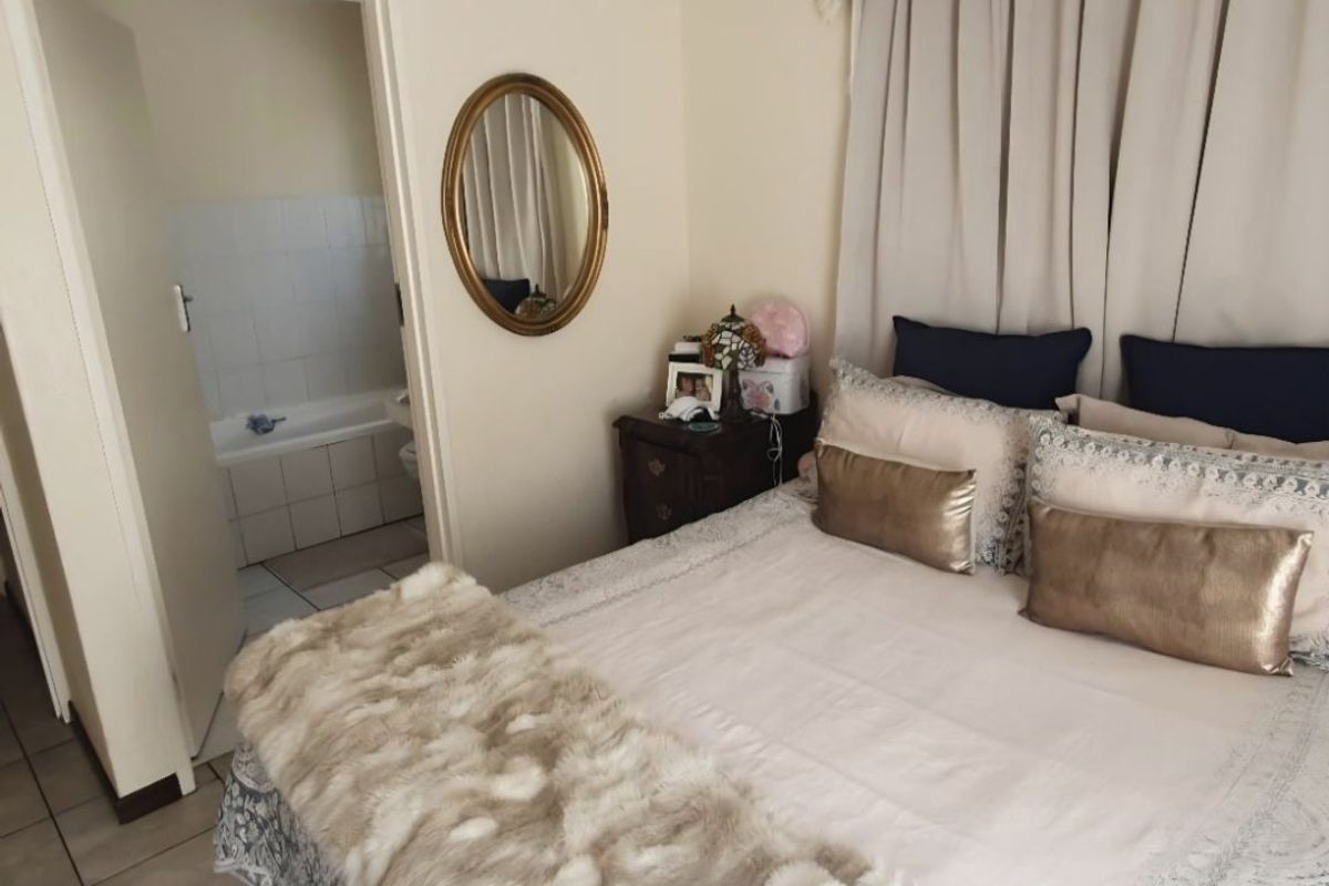 A bedroom featuring tiled flooring and direct access to an en-suite bathroom, providing a functional and convenient layout.