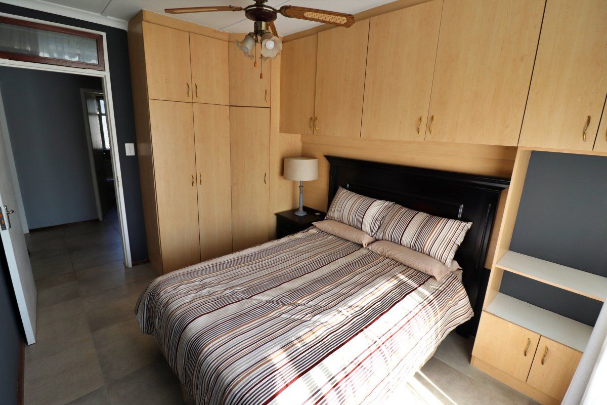 Bedroom featuring extensive built-in wooden cabinetry, a ceiling fan, and tiled flooring, offering ample storage space.