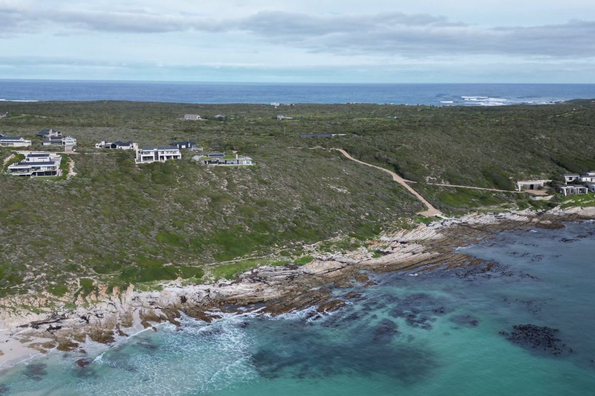 An aerial view of the coastal residential area, showcasing the natural landscape, rocky shoreline, and surrounding vegetation.