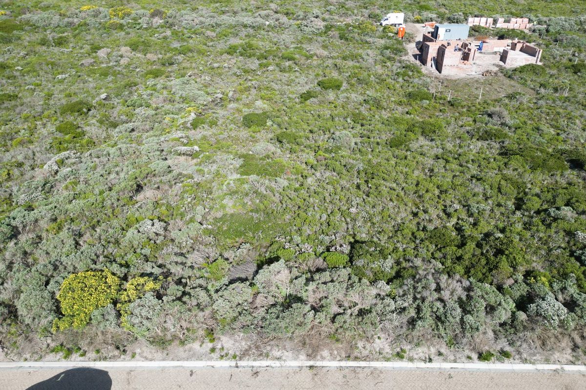 Aerial view of a vacant residential plot featuring native vegetation and the initial brickwork of a building structure under construction.