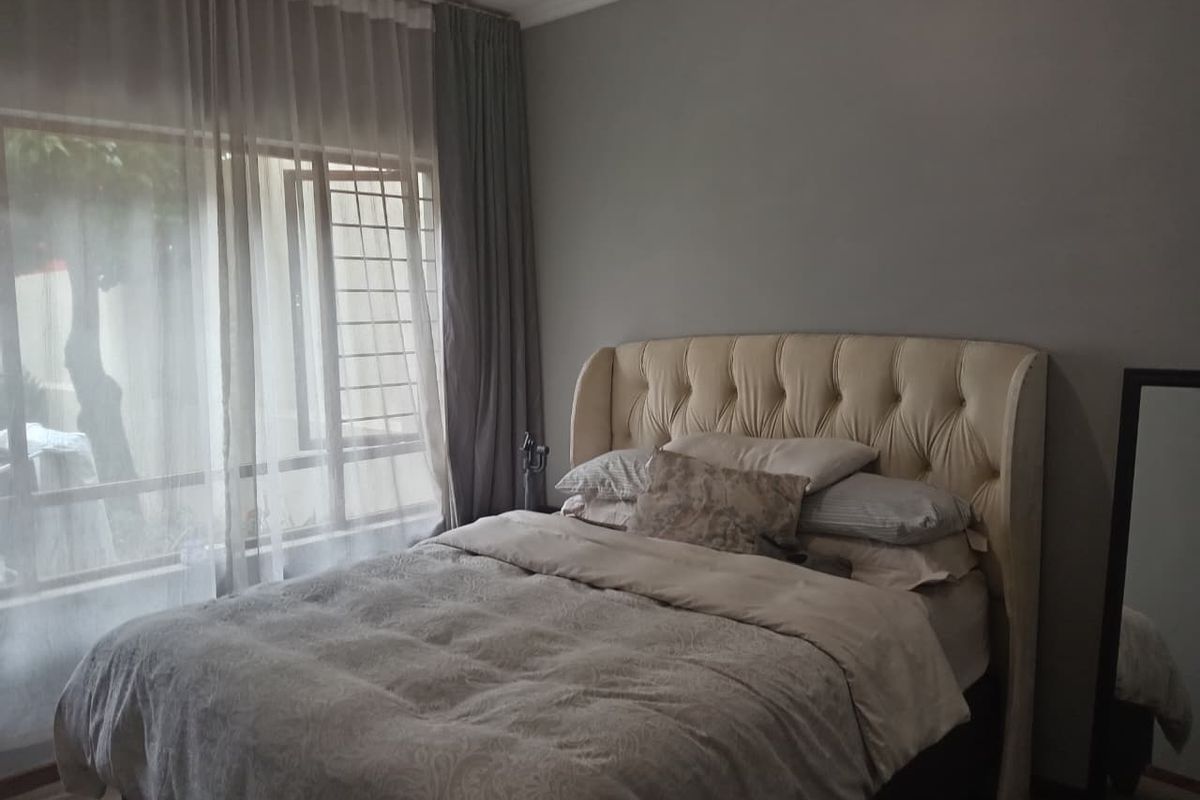 A well-lit bedroom featuring a large sliding door with security bars and neutral wall finishes.