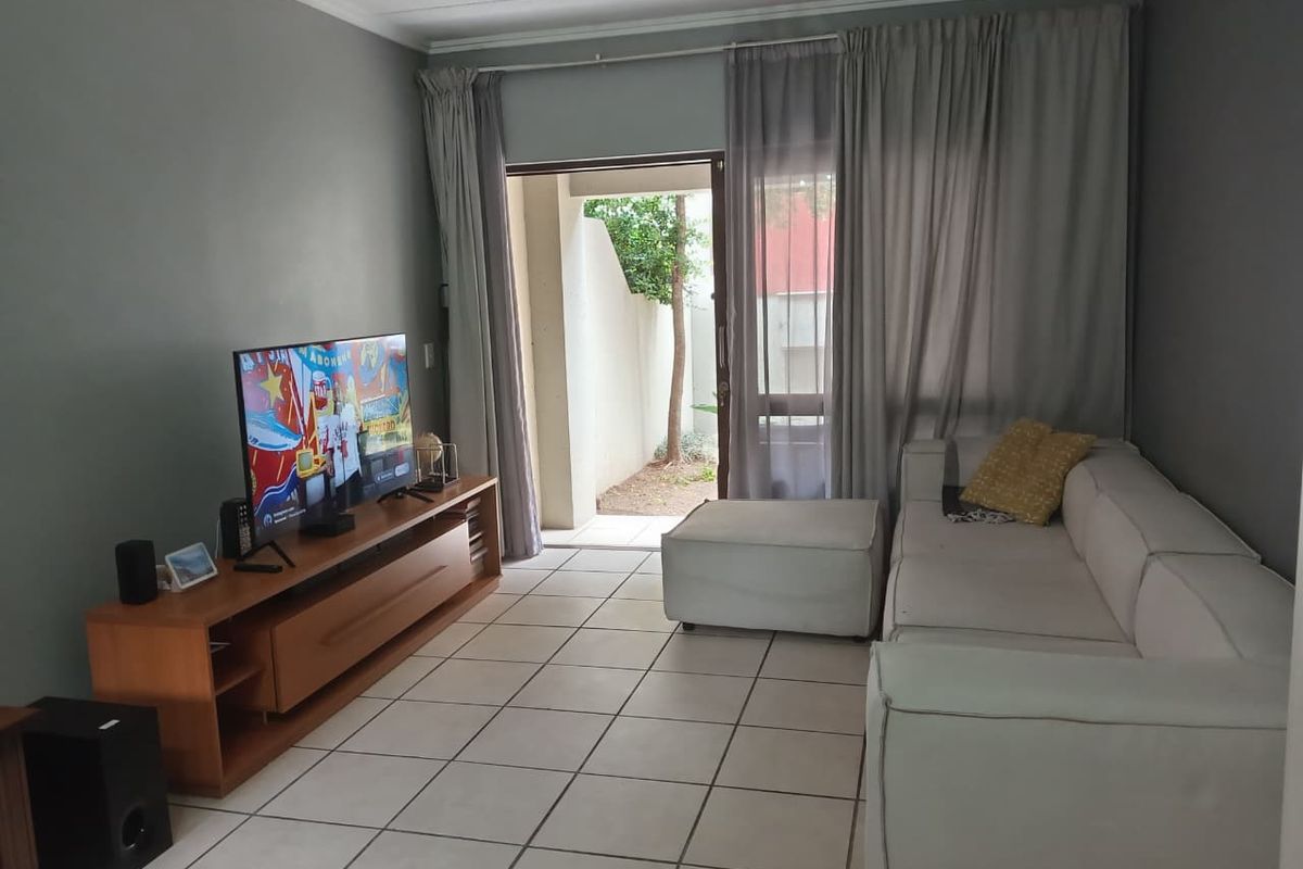A living room featuring tiled flooring and a sliding glass door providing access to an outdoor patio area.