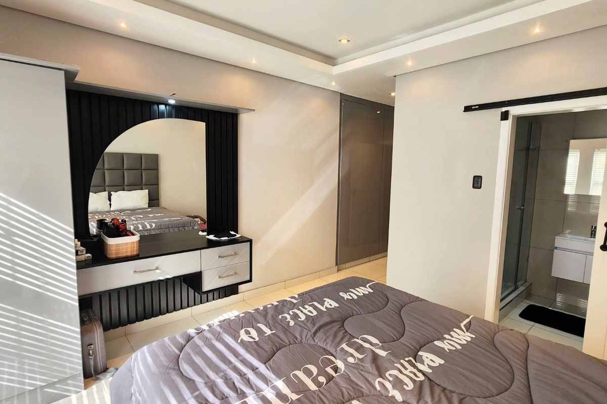 Modern bedroom featuring a built-in vanity, recessed ceiling lighting, ample built-in cupboard space, and a sliding barn door leading to an en-suite bathroom.