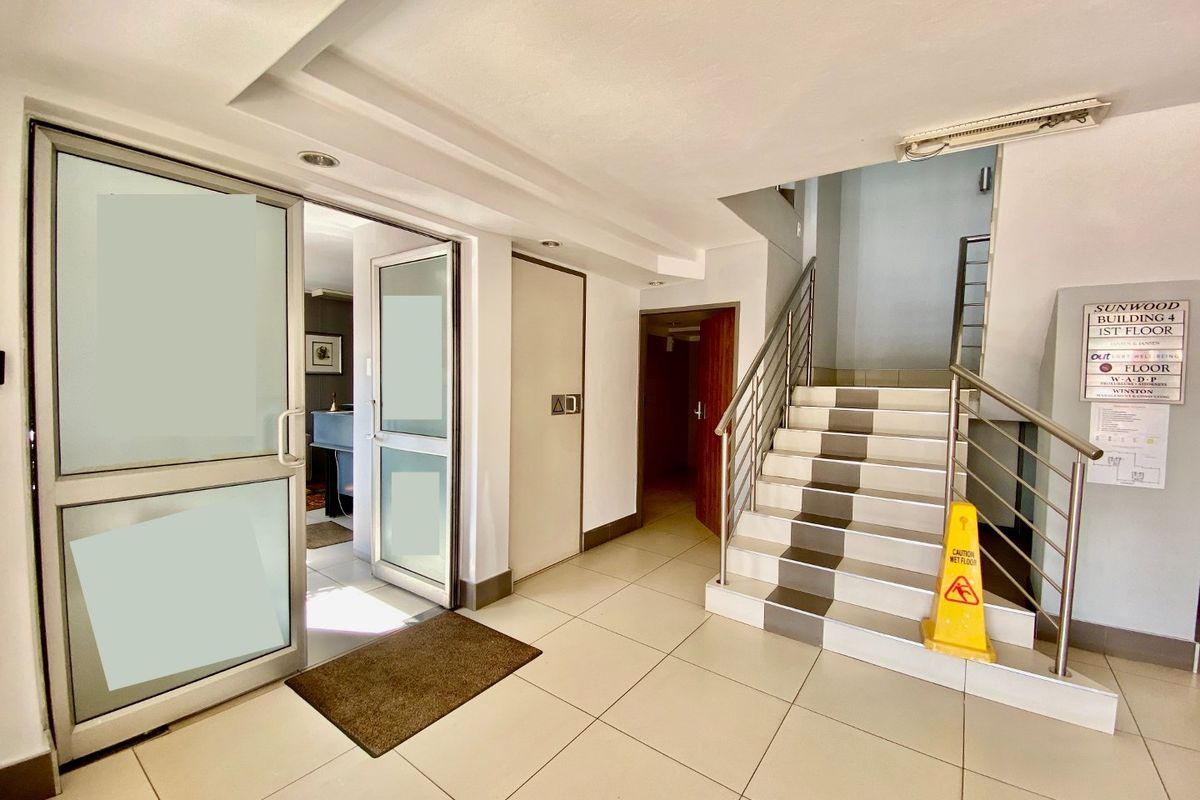 Commercial building entrance lobby featuring tiled flooring, a staircase with stainless steel handrails, and a directory board for tenants.