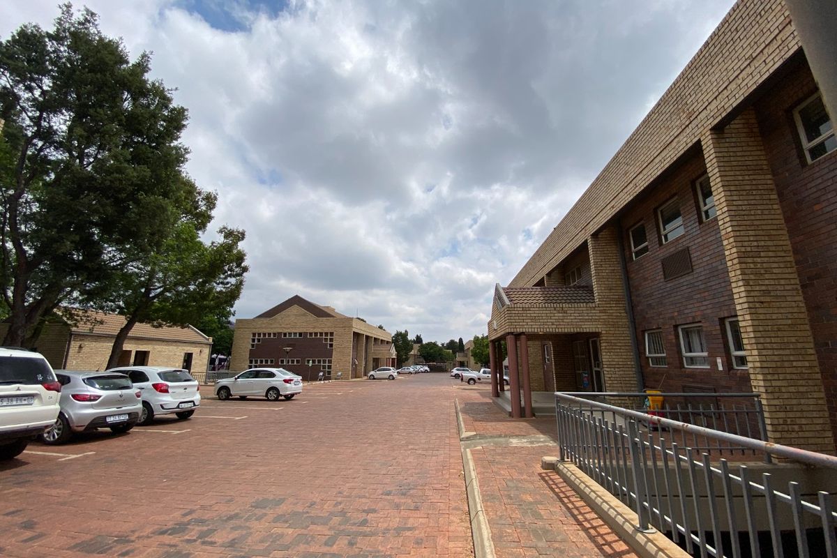 Exterior view of a commercial office complex featuring brick buildings, a paved parking area, and metal safety railings.