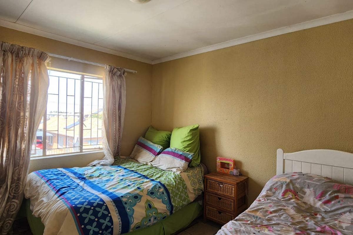 A bedroom featuring a built-in wardrobe, security bars on the window, and coving detail. The room requires cosmetic updates to the wall finishes.