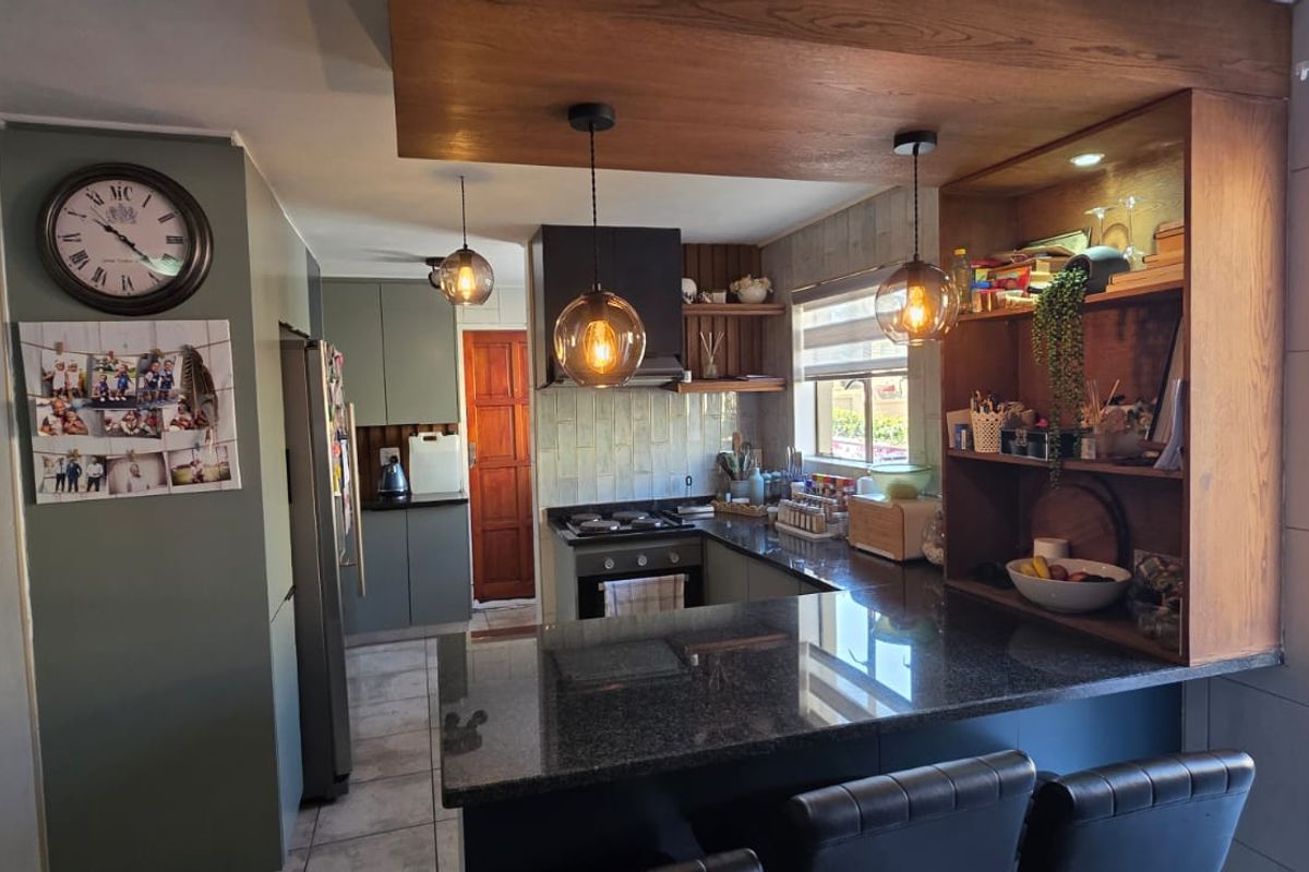 Modern kitchen featuring granite countertops, built-in cabinetry, gas hob, and integrated oven, seamlessly connected to the living area and staircase.