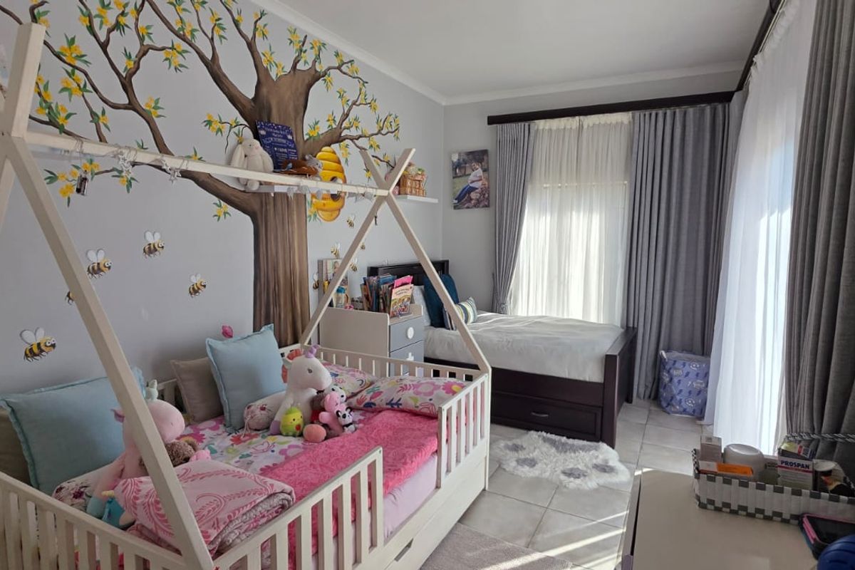 A well-maintained bedroom featuring tiled flooring, neutral wall finishes, and a sliding door providing access to natural light.