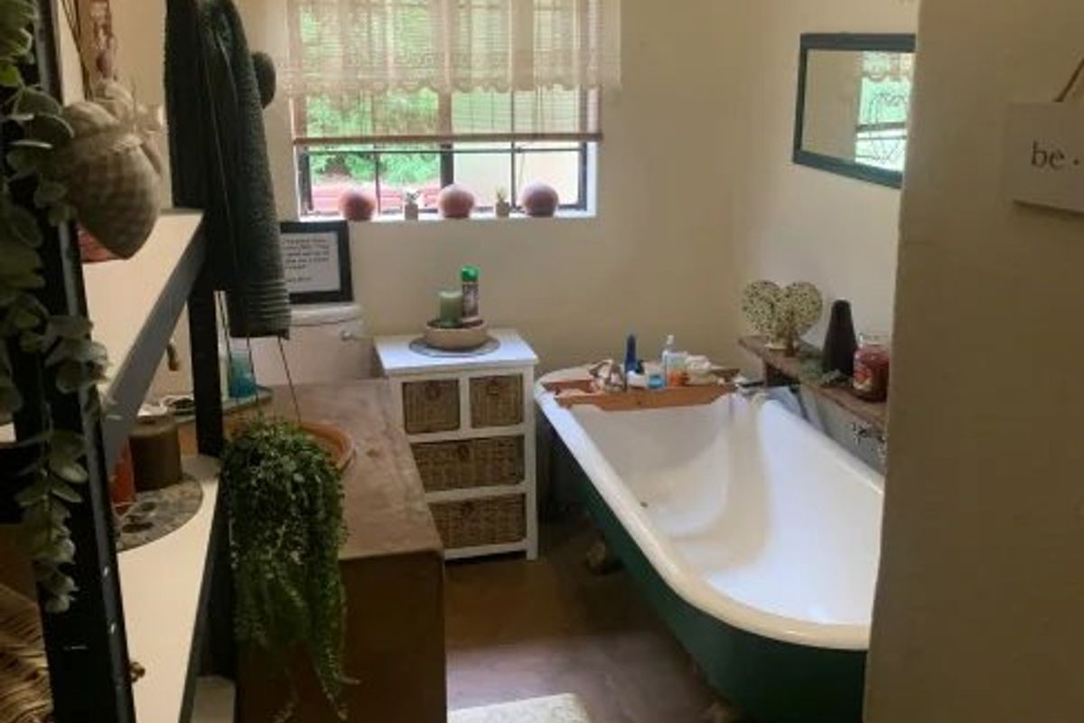 A bathroom featuring a classic clawfoot bathtub, a toilet, and a window, providing a functional space with potential for cosmetic updates.