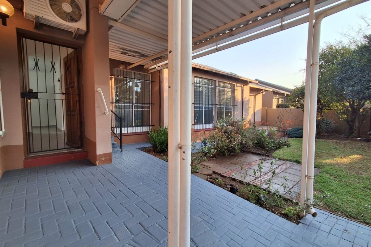 A covered patio area featuring paved flooring, metal support columns, and direct access to a private garden space.