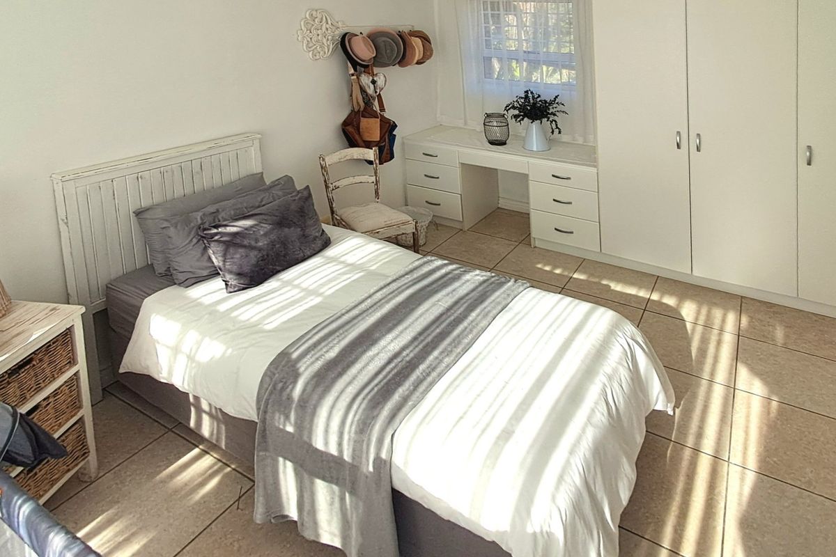 A bedroom featuring built-in cupboards, a integrated vanity unit, and tiled flooring, illuminated by natural light.