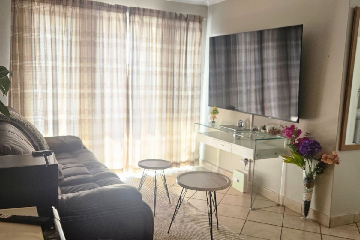 A living room area featuring tiled flooring and large window curtains, providing a functional space with direct access to adjacent areas.