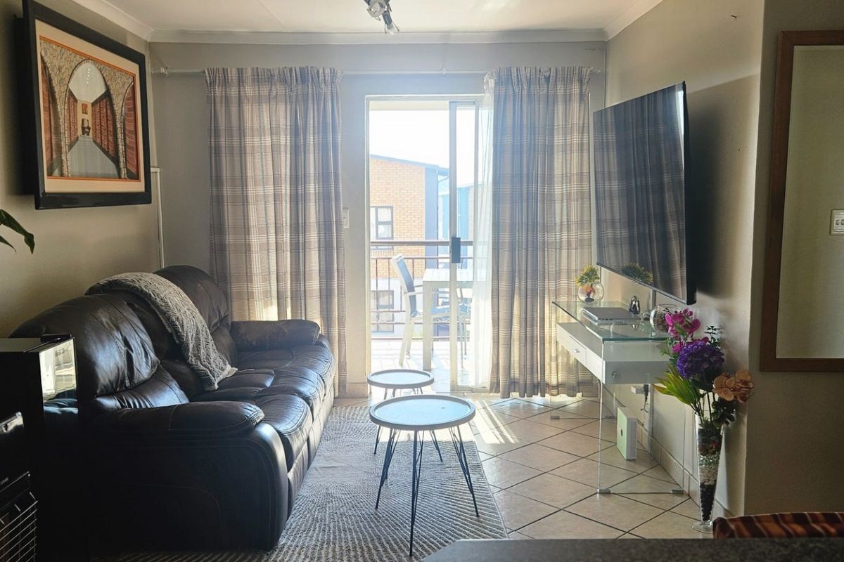 A comfortable living room featuring ceramic floor tiles and a sliding glass door that provides access to a private balcony.