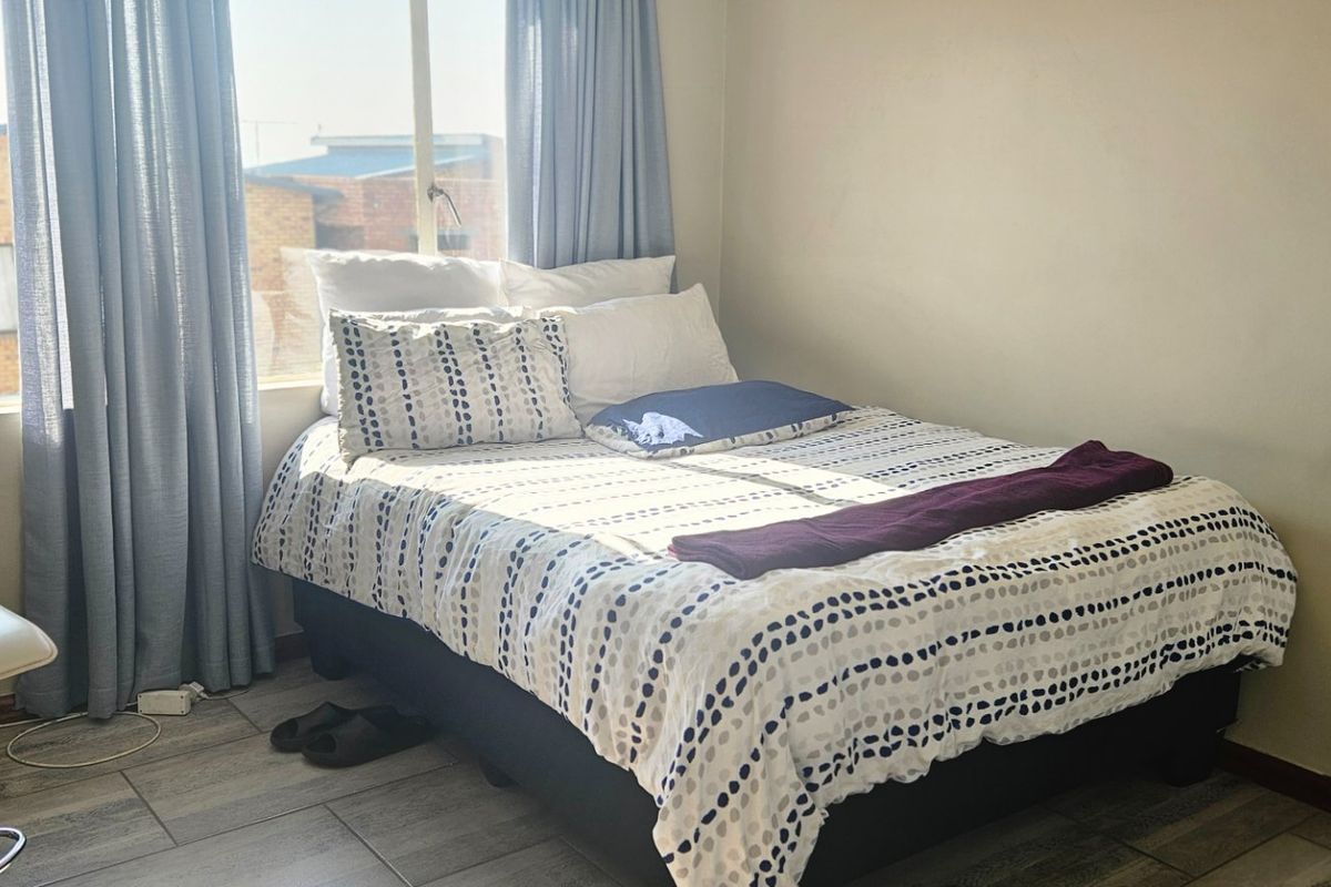A functional bedroom featuring tiled flooring and natural light from a window, providing a comfortable living space.