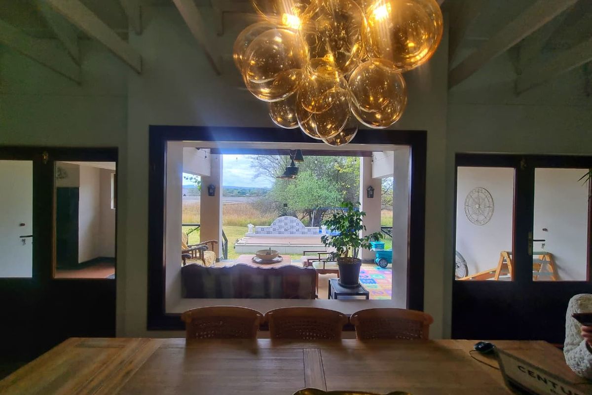 Spacious living area featuring exposed beam ceilings and a large picture window providing a seamless view of the outdoor patio and garden.