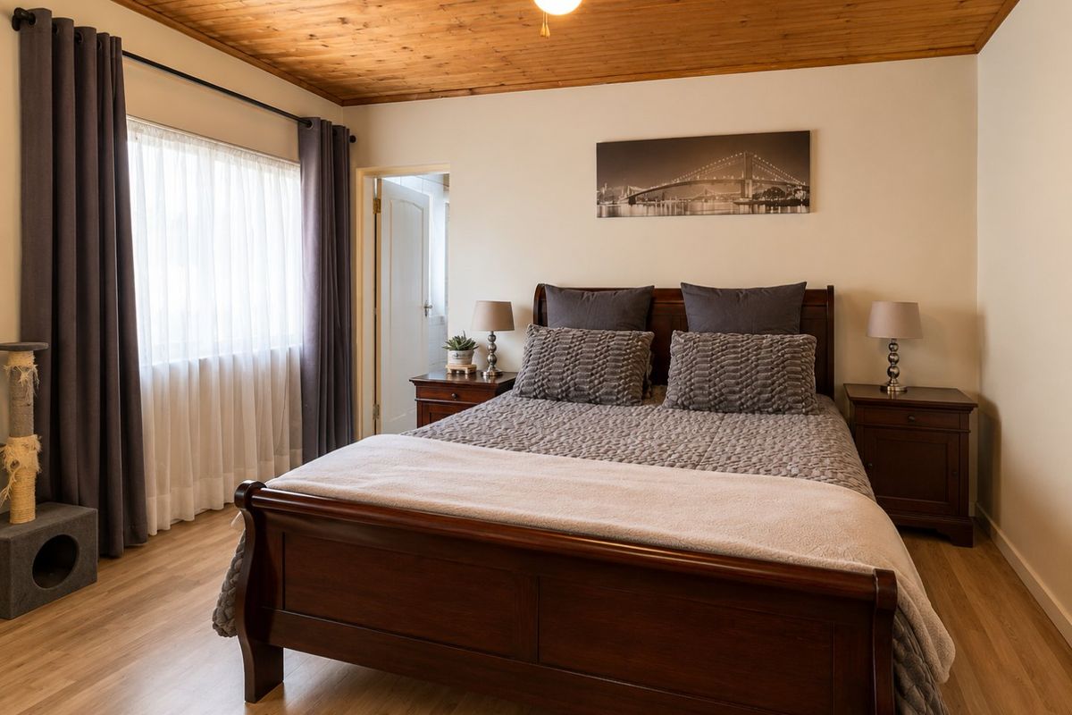 A well-maintained bedroom featuring warm timber tongue and groove ceilings, laminate flooring, and neutral wall finishes, providing a comfortable and inviting living space.