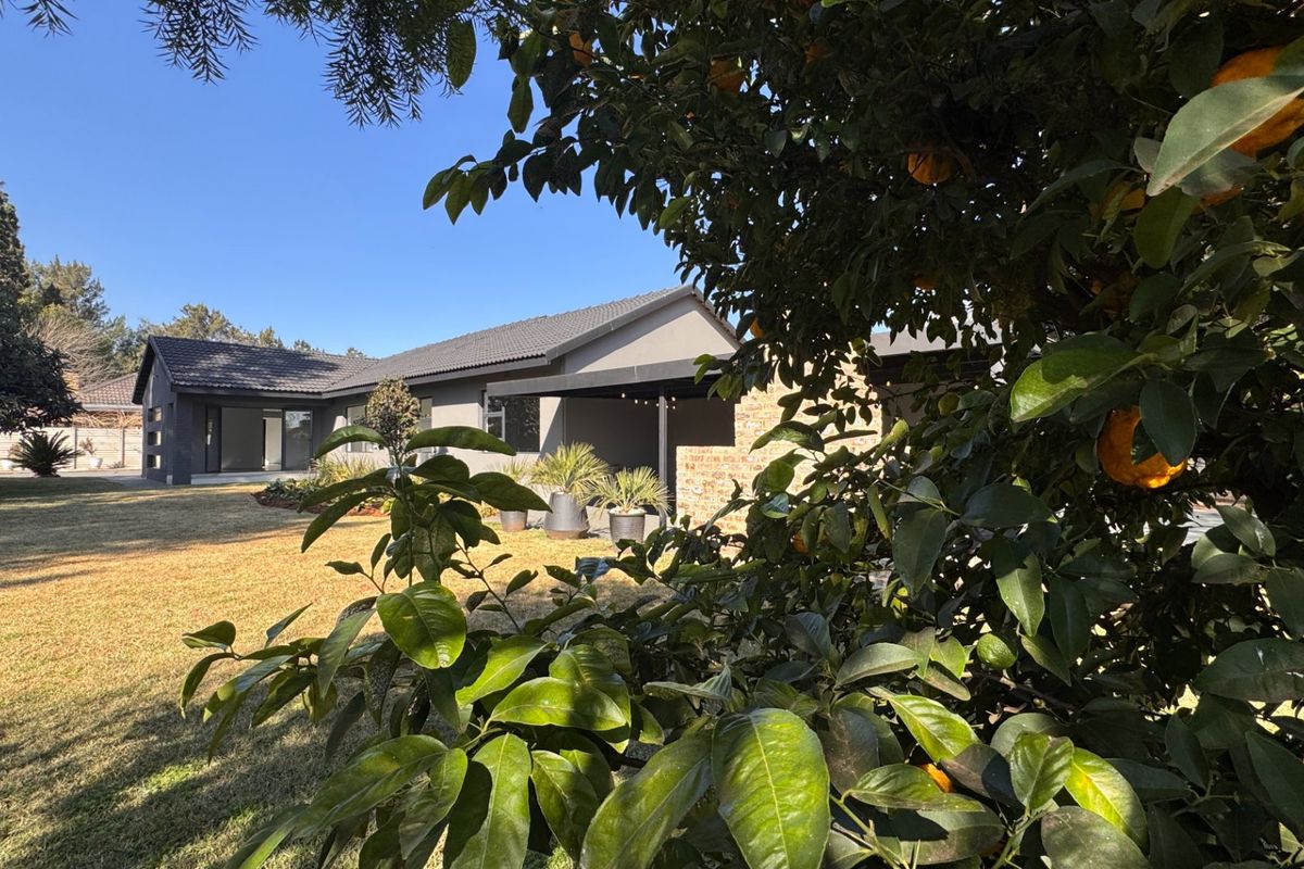 A view of the rear elevation of the house featuring a covered patio area, brick accents, and a well-maintained garden.