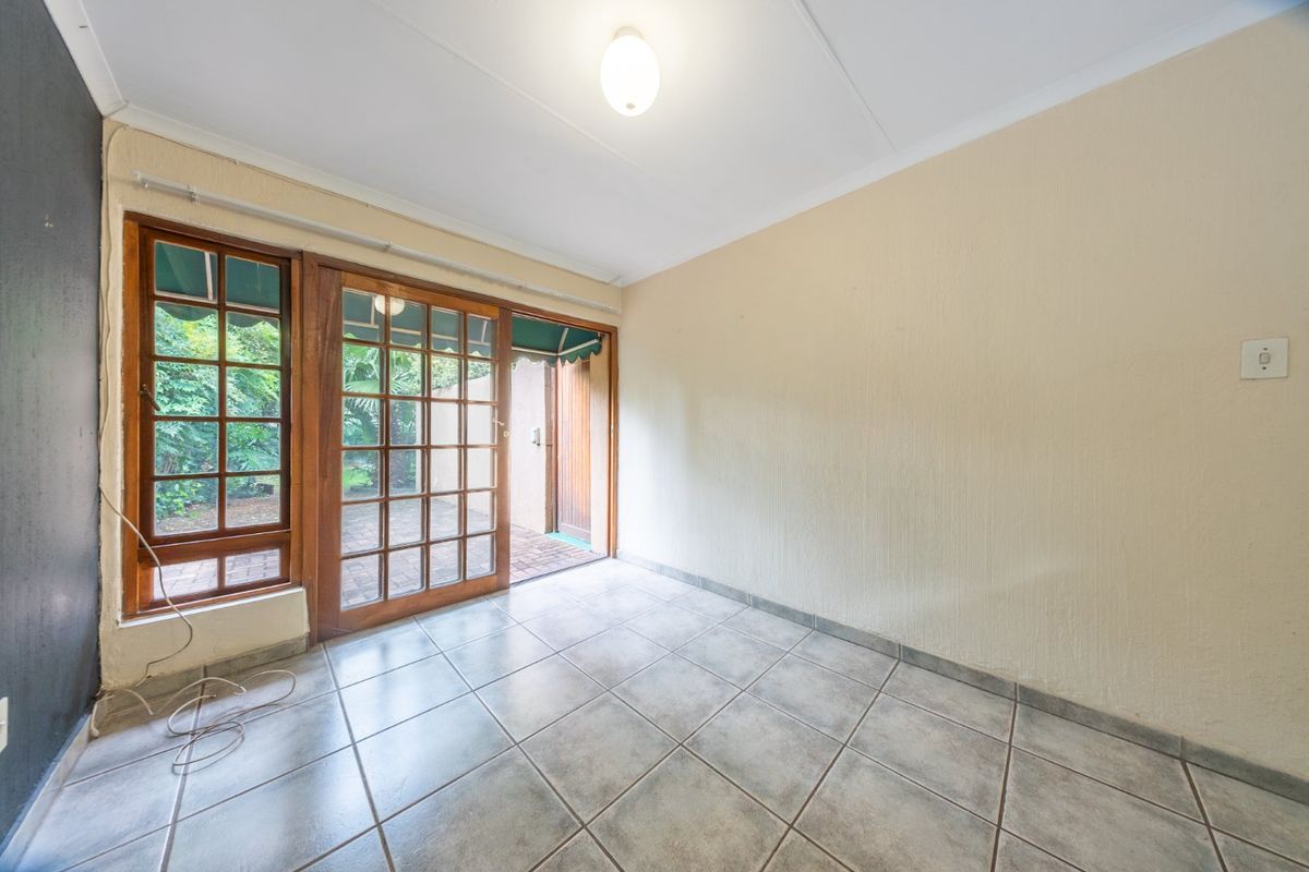 An empty living room featuring tiled flooring and a sliding wooden door providing direct access to an outdoor patio area.