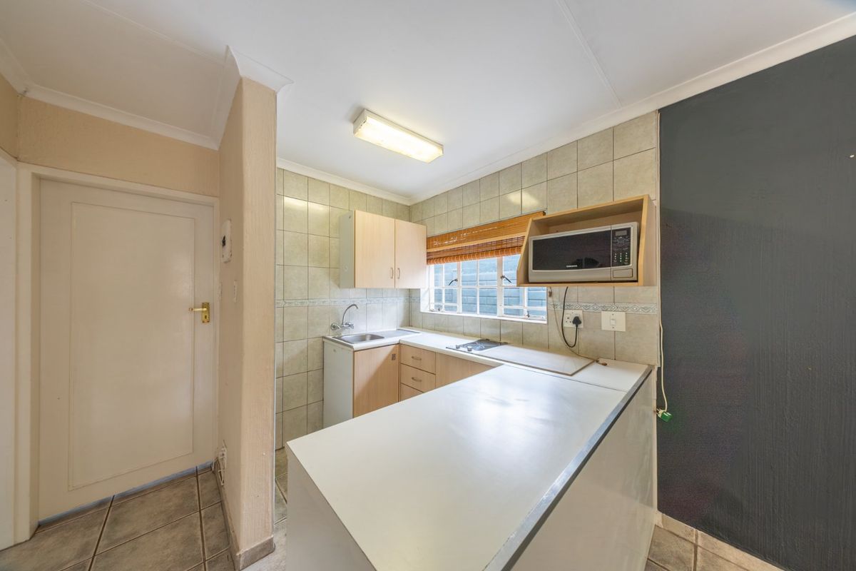 A compact, functional kitchen featuring built-in cabinetry, tiled backsplash, and a dedicated microwave shelf, offering a clean and practical layout.