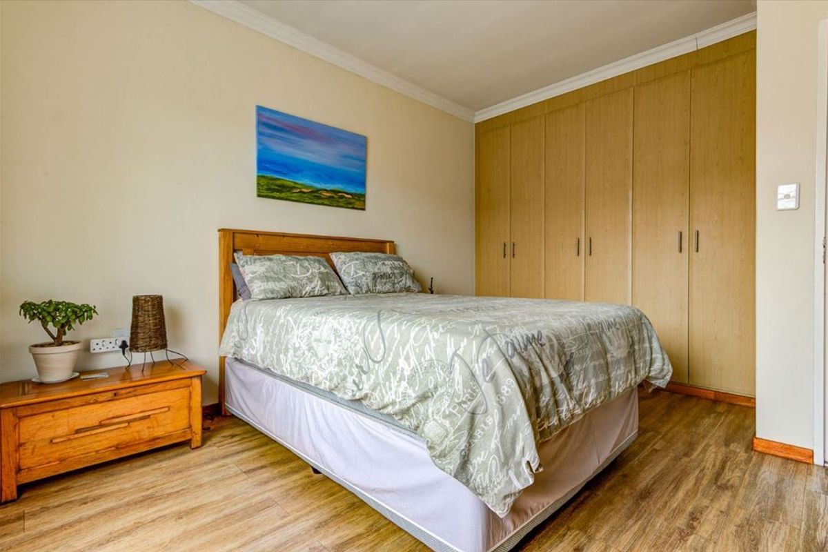 A well-maintained bedroom featuring laminate flooring and ample built-in cupboard storage space.