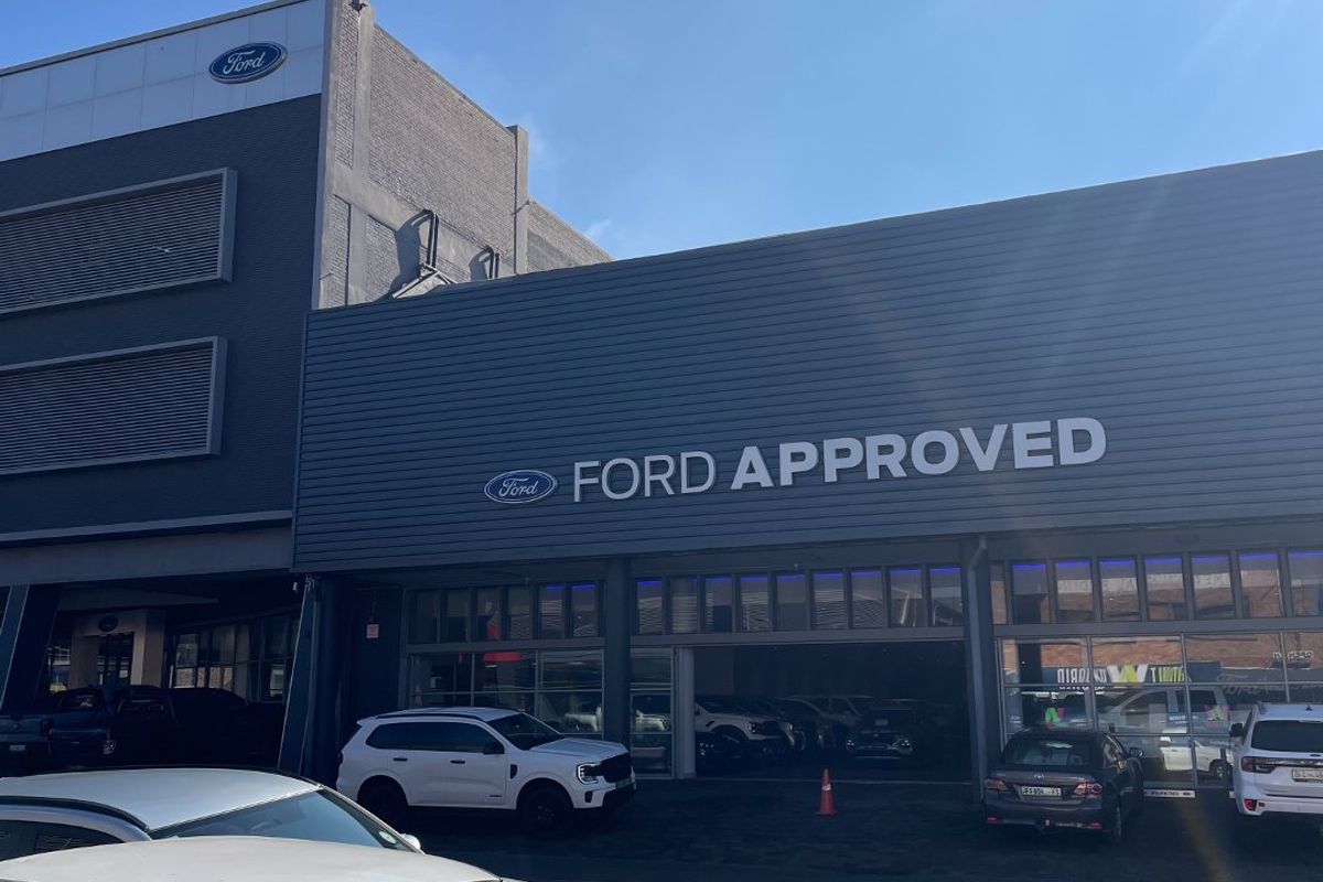 Front facade of a commercial Ford Approved dealership building featuring modern metal cladding and large glass storefront windows.
